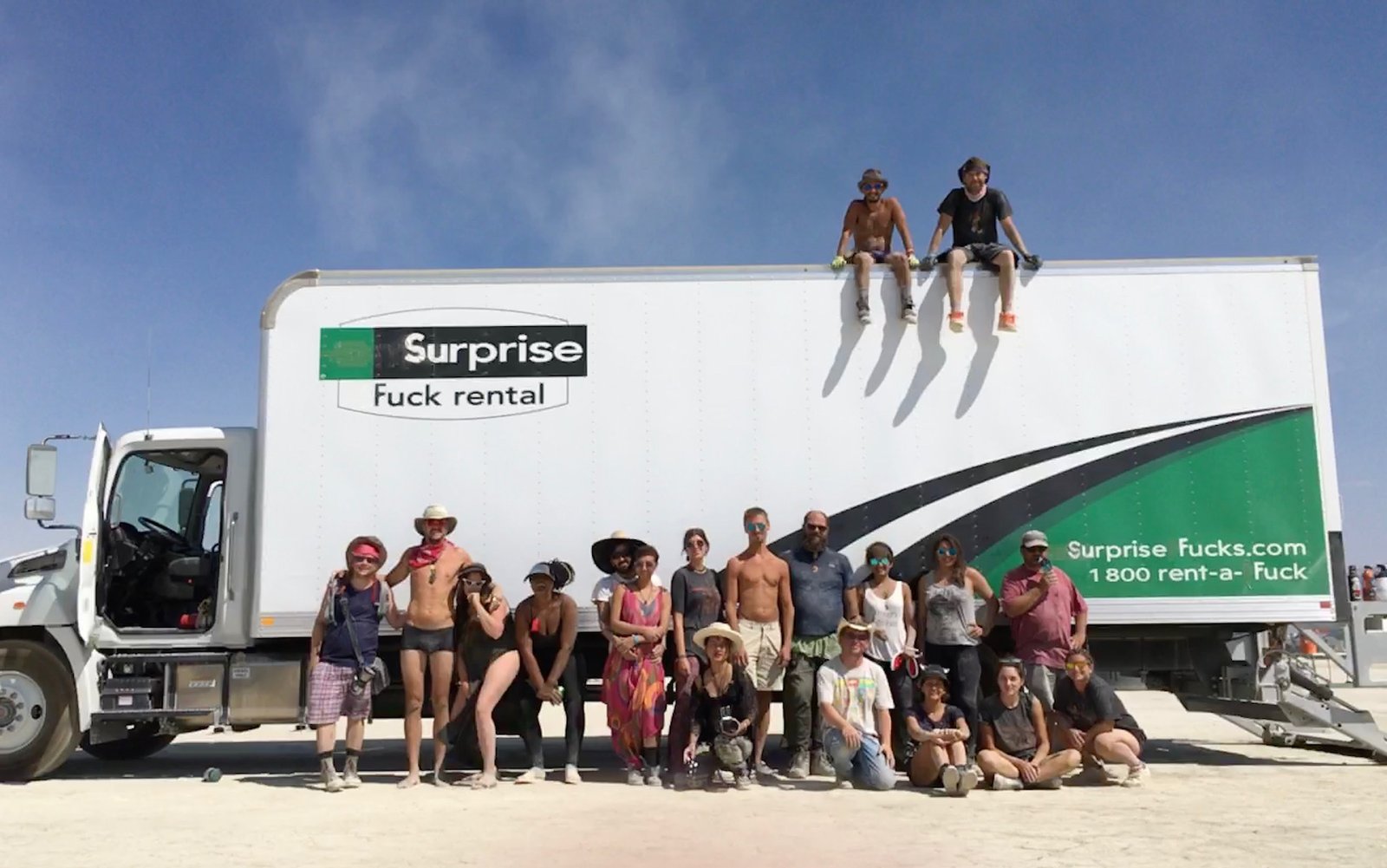 The Surprise Fuck Rental crew posing in front of the truck on the playa, 2018